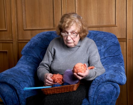 The grandmother holds a ball of threads in a hand 