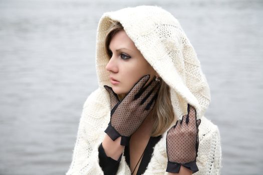 The thoughtful girl in  knitted dress on a background of water