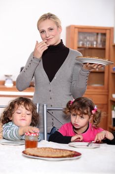 mother holding a dish of crepes and children waiting to eat crepes