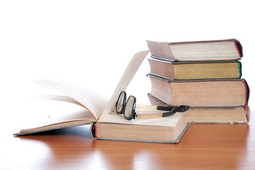 Old glasses and the old book on a white background