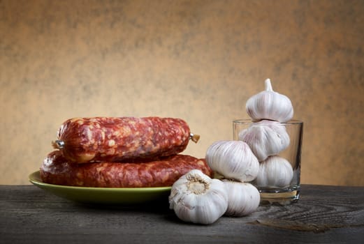Still-life with sausage and garlic on a wooden table
