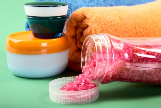 Cosmetic cream and towels on a green background