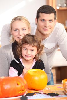 Little girl with parents preparing pumpkin for Halloween