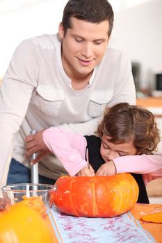Dad and his daughter carving pumpkins in the kitchen