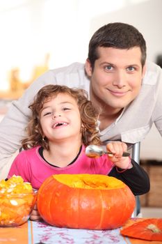 a father and his little girl laughing and eating a pumpkin