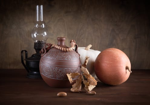 Still-life with a jug an oil lamp and pumpkins on a table