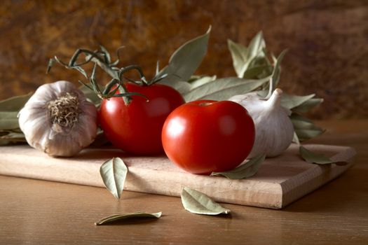 Tomatoes garlic and bay leaf branches on a kitchen table