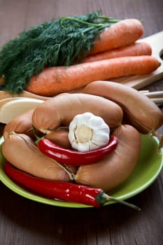 Sausages with spices and vegetables on an old wooden table