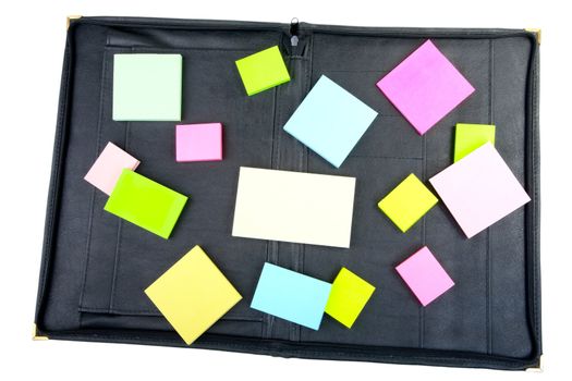 Leather folder with the scattered piles of stickers on a white background