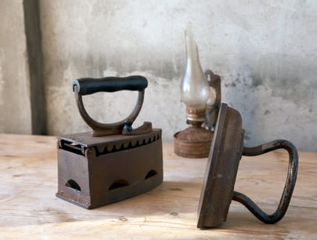 Old irons and oil lamp on a wooden table