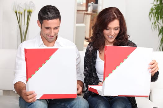 A couple looking at their pizzas.