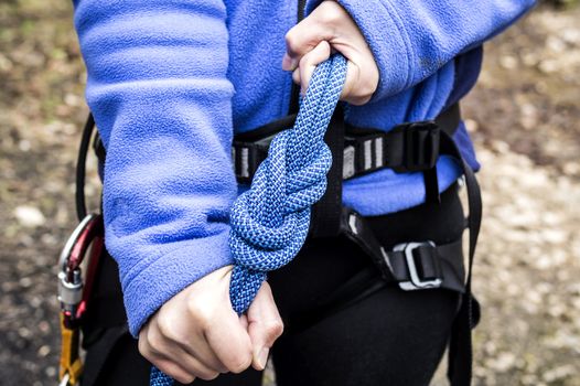 female hands holding a climbing rope with a secure node