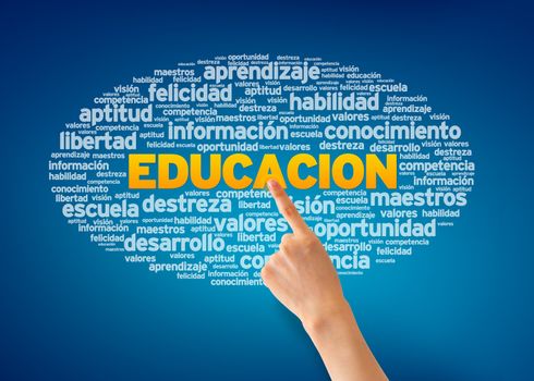Hand pointing at a Educacion Word Cloud on blue background.