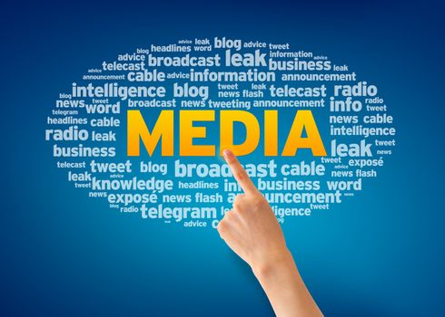 Hand pointing at a Media Word Cloud on blue background.