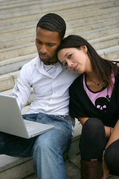 Young couple on some steps with a laptop