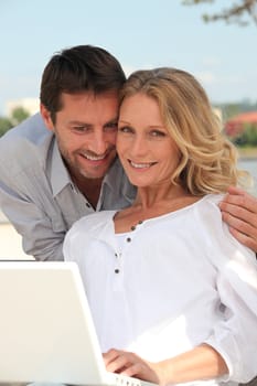 Couple sat outdoors with laptop