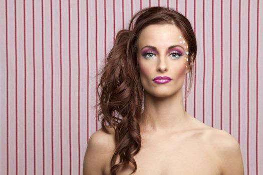 Young woman with colorful makeup and star candy glued to her face

