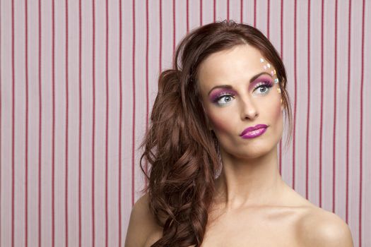 Young woman with colorful makeup and star candy glued to her face

