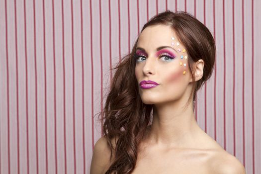 Young woman with colorful makeup and star candy glued to her face
