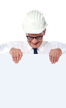 Aged builder with a helmet on his head holding a blank poster