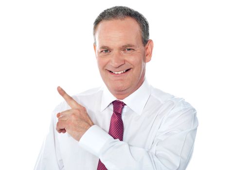 Smiling businessman pointing away. Copyspace concept
