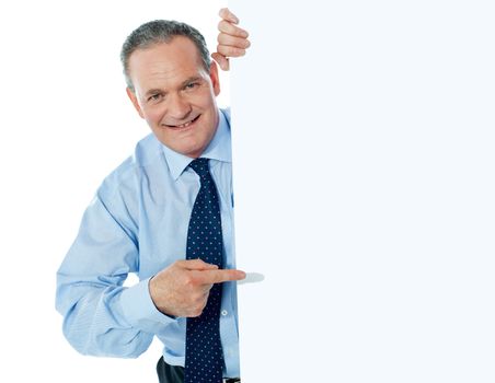 Salesman smiling and pointing towards blank billboard isolated over white