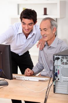 Younger and older men looking at a computer