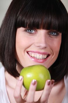Woman with a big smile and a green apple