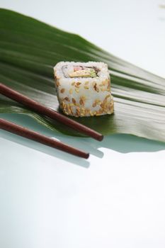 Single sushi resting on green leaf