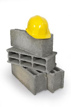 Yellow hard hat resting on pile of breeze blocks