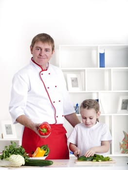 portrait of father and daughter cooking salad together in the kitchen