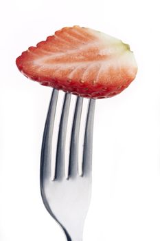 slice of strawberry pierced on a fork against plain background