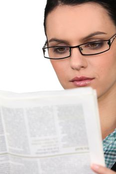 Young woman in glasses reading a newspaper