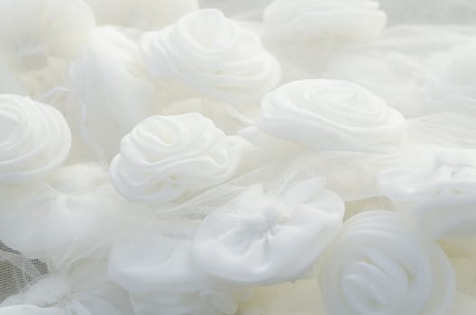 Close-up of beautiful and glowing cloth white roses on wedding gown