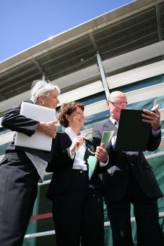 Businesspeople discussing a file in front of a building