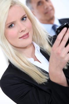 Striking young woman with mobile phone and boss in the background