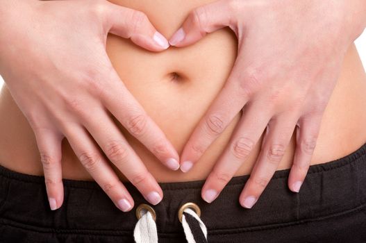 Woman making a heart symbol over her tummy with her hands, isolated in white