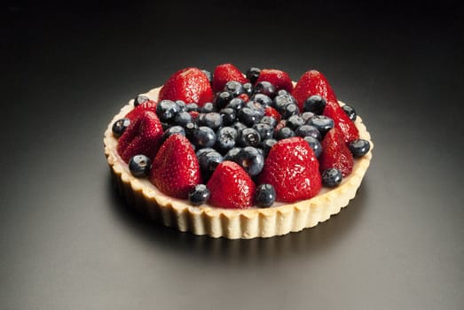 fruit pie with strawberries and blueberries on black