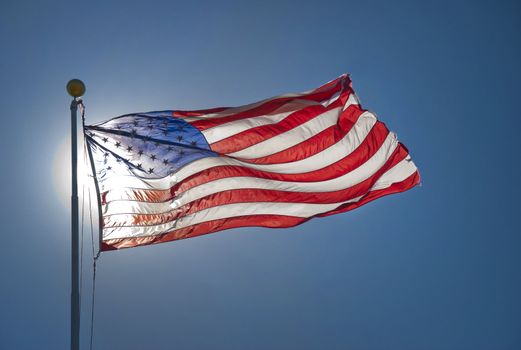 American flag fluttering in the wind back lit by sun