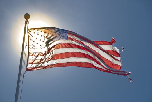 American flag fluttering in the wind back lit by sun