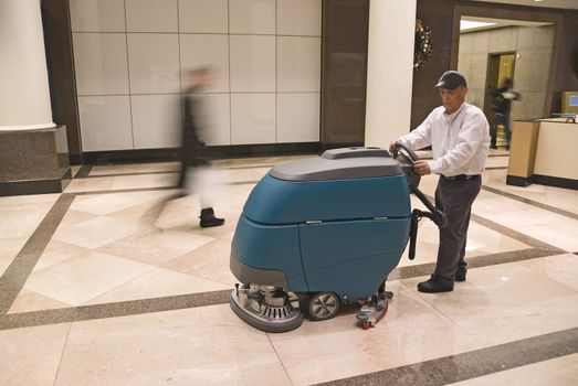 Floor cleaning machine operator in commercial building lobby