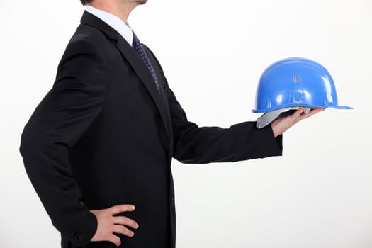 architect in profile holding out hard hat