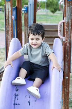 Cute baby playing on sliding board, smiling