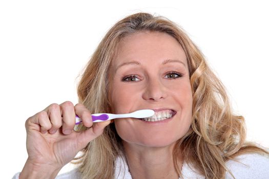 45 years old blonde woman is brushing her teeth