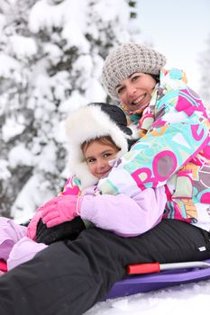 Mother and daughter sledging together