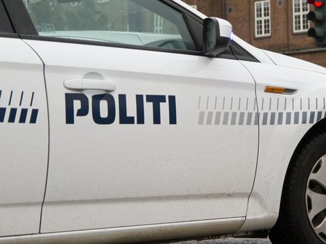 detail of a danish police car in front of a red street light