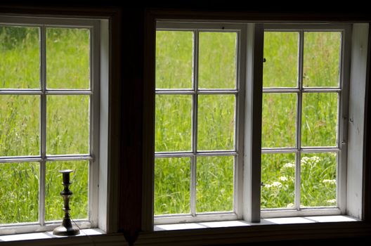 view on a meadow out of old windows with a candle stick
