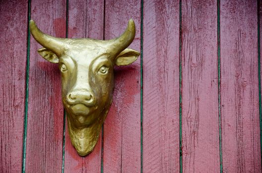 Golden head of a cow on a red wall as advertisement for a butcher's shop