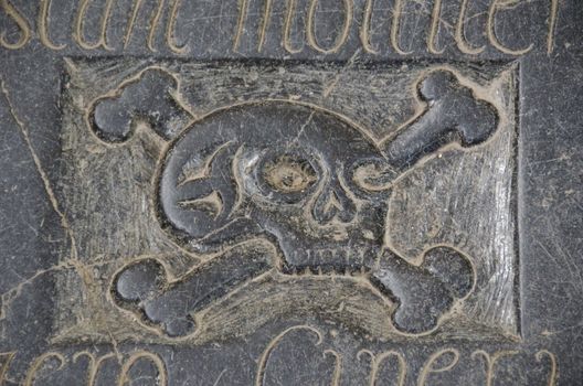 silhouette of a human skull and bones on a black grave stone