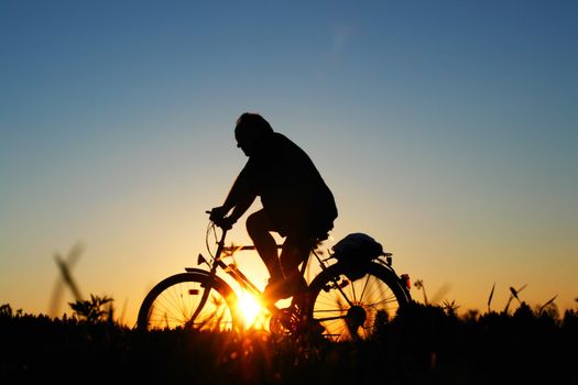 biker on a meadow at the sunset